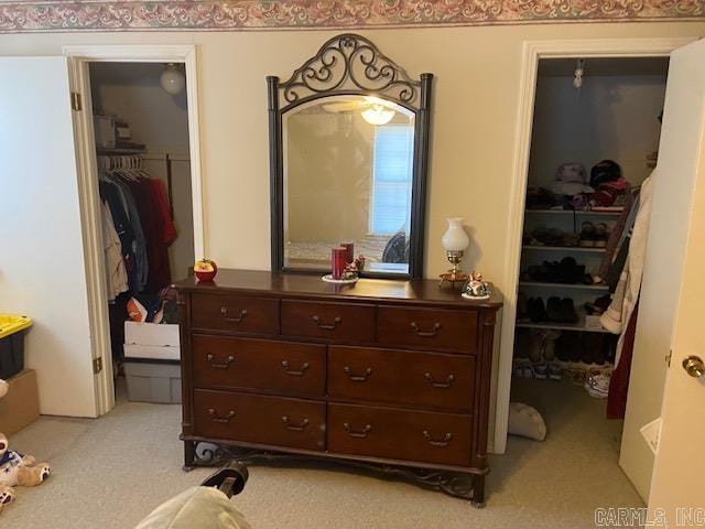 bedroom with a walk in closet, light colored carpet, and a closet