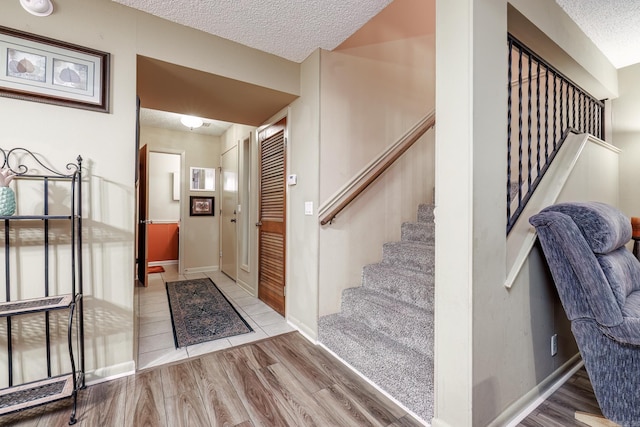 foyer entrance featuring a textured ceiling and light wood-type flooring