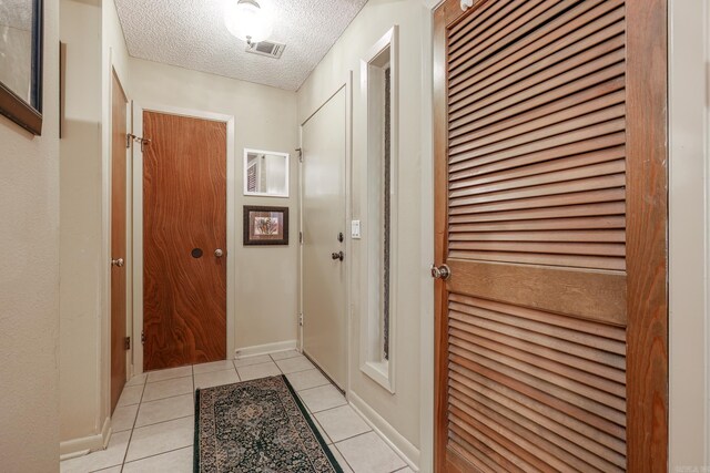 hall featuring a textured ceiling and light tile patterned flooring