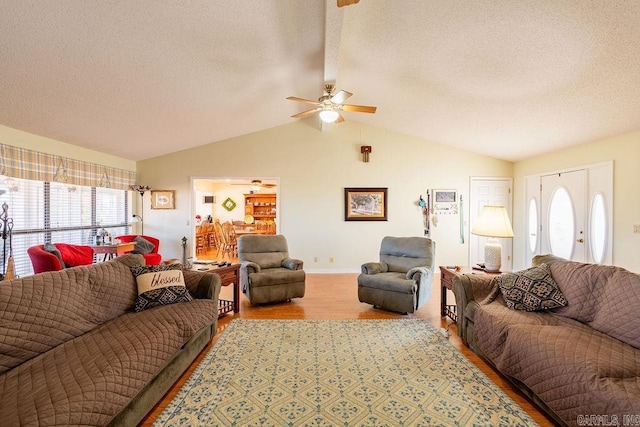 living room with lofted ceiling, ceiling fan, light wood-type flooring, and a textured ceiling