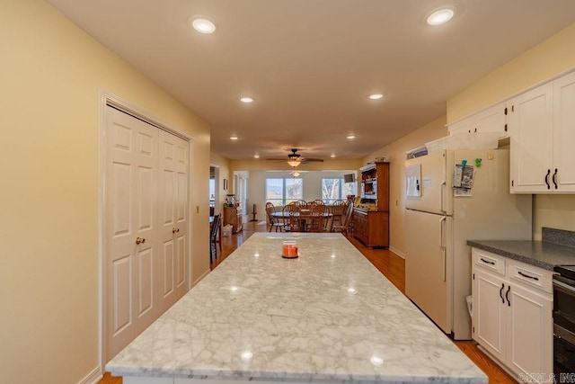 kitchen with ceiling fan, light stone countertops, white cabinetry, and dark wood-type flooring