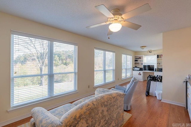 living room featuring a textured ceiling, light wood-type flooring, and ceiling fan