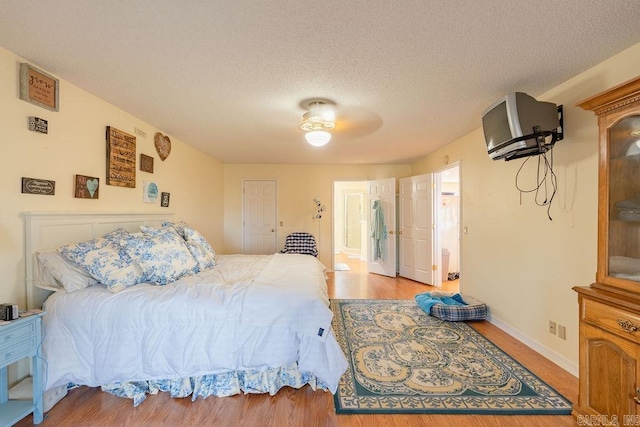 bedroom featuring ceiling fan, light wood-type flooring, and a textured ceiling