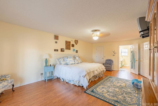 bedroom featuring hardwood / wood-style floors, ceiling fan, a textured ceiling, and ensuite bath