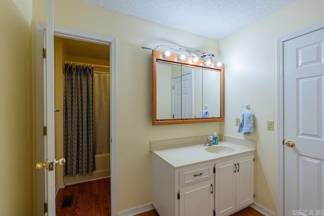 bathroom featuring shower / tub combo, vanity, wood-type flooring, and a textured ceiling