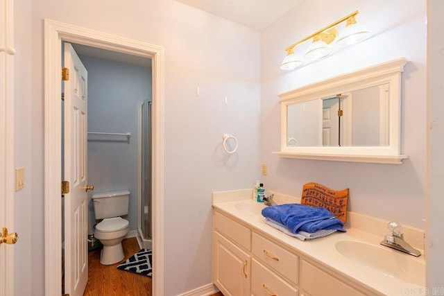 bathroom with hardwood / wood-style floors, vanity, an enclosed shower, and toilet