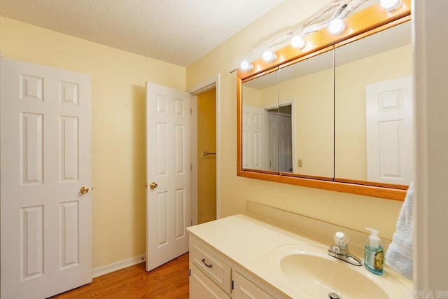 bathroom with vanity, wood-type flooring, and a textured ceiling