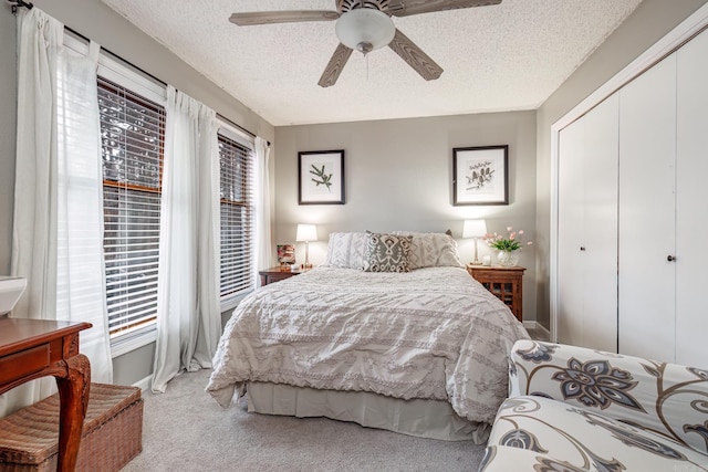 bedroom featuring a closet, a textured ceiling, light colored carpet, and ceiling fan