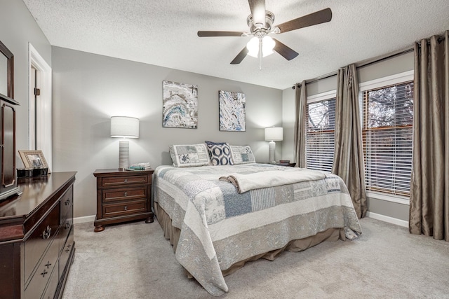 bedroom with ceiling fan, light carpet, and a textured ceiling