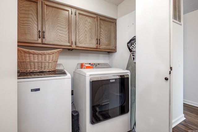 laundry area featuring dark hardwood / wood-style floors, cabinets, a textured ceiling, and washing machine and clothes dryer