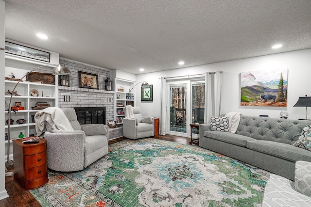 living room with a textured ceiling, hardwood / wood-style flooring, and a brick fireplace