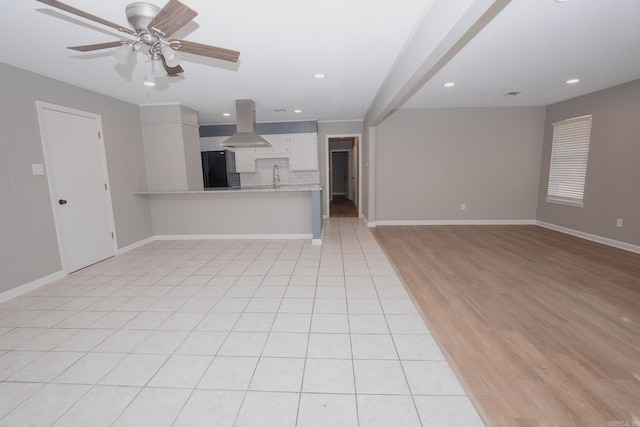 unfurnished living room with ceiling fan, sink, and light wood-type flooring