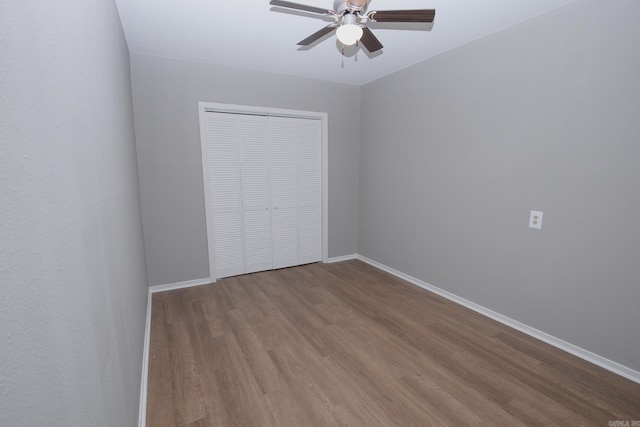 unfurnished bedroom featuring ceiling fan, a closet, and wood-type flooring