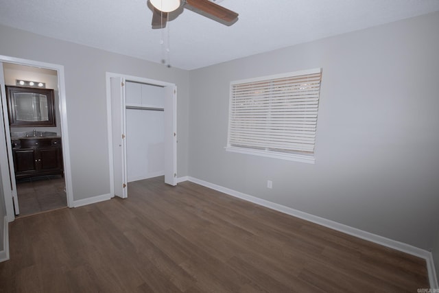 unfurnished bedroom featuring a closet, dark hardwood / wood-style flooring, ensuite bathroom, and ceiling fan