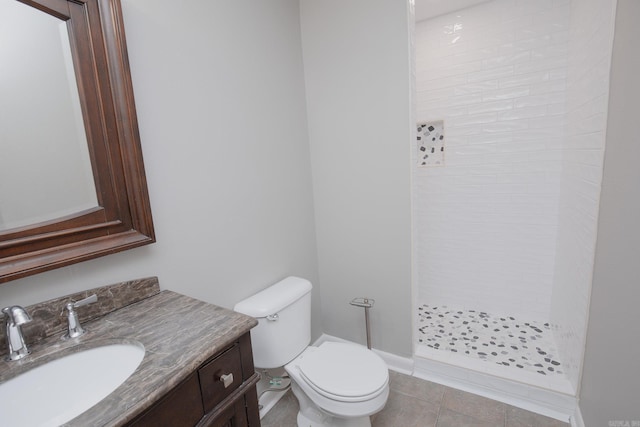 bathroom featuring tile patterned flooring, toilet, vanity, and tiled shower