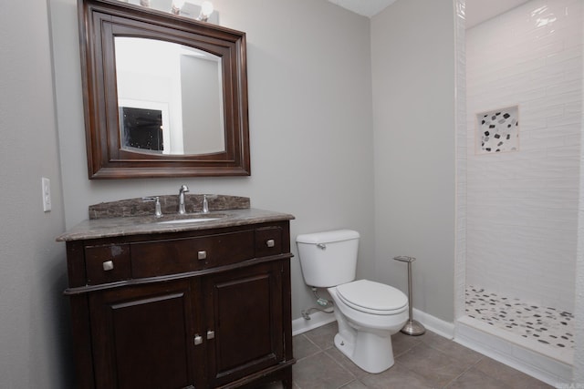 bathroom featuring tile patterned flooring, vanity, tiled shower, and toilet