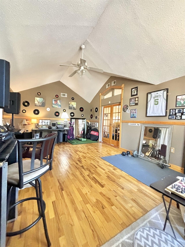 living room featuring hardwood / wood-style floors, french doors, vaulted ceiling, ceiling fan, and a textured ceiling