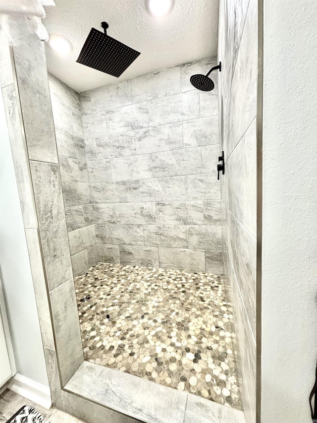 bathroom featuring a tile shower and a textured ceiling