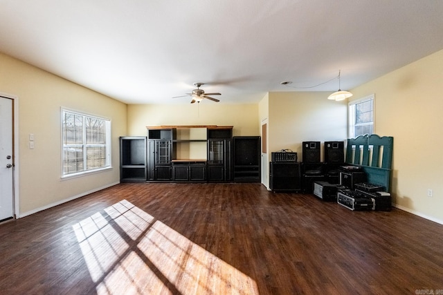 unfurnished living room with dark hardwood / wood-style flooring and ceiling fan