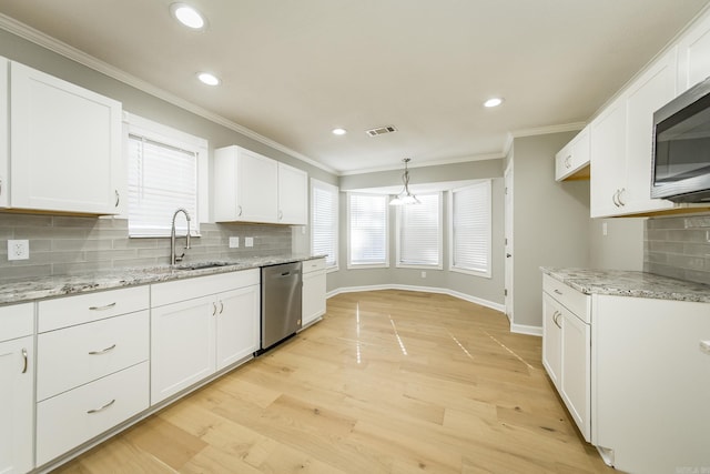 kitchen with appliances with stainless steel finishes, sink, decorative light fixtures, light hardwood / wood-style flooring, and white cabinetry