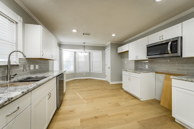 kitchen featuring appliances with stainless steel finishes, light wood-type flooring, tasteful backsplash, sink, and white cabinetry