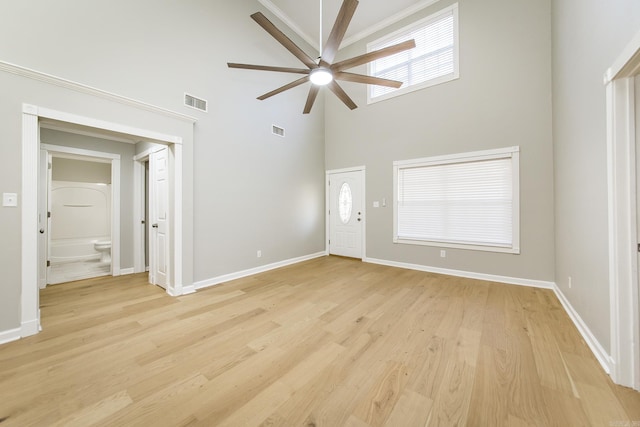 unfurnished living room with a towering ceiling, light hardwood / wood-style floors, and ceiling fan