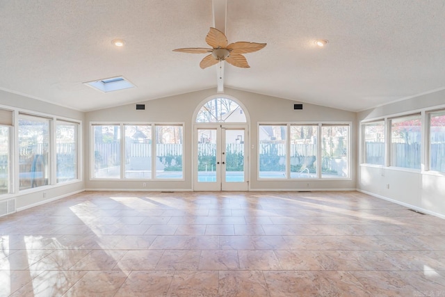 unfurnished sunroom featuring ceiling fan, a healthy amount of sunlight, lofted ceiling with skylight, and french doors