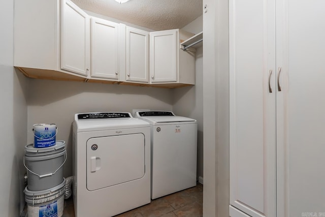 laundry area featuring cabinets, light tile patterned floors, a textured ceiling, and washing machine and dryer