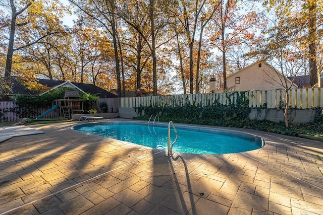 view of pool featuring a diving board, a playground, and a patio