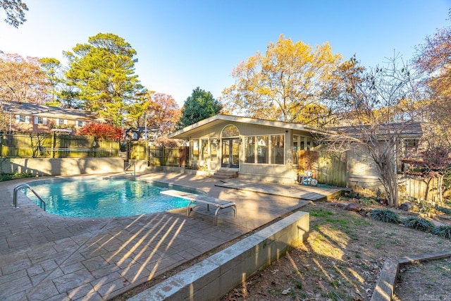 view of pool featuring a sunroom, a diving board, and a patio area