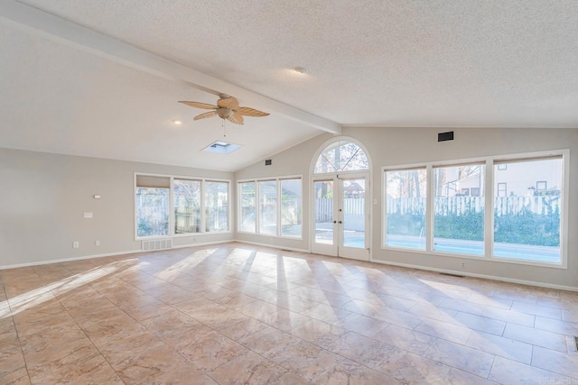 empty room with french doors, a textured ceiling, ceiling fan, and vaulted ceiling with skylight