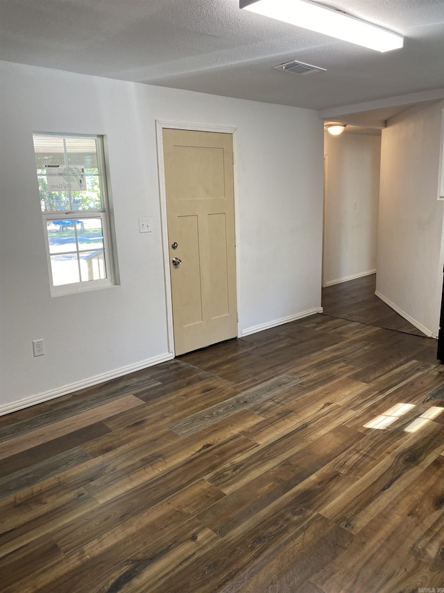 unfurnished room featuring a textured ceiling and dark wood-type flooring