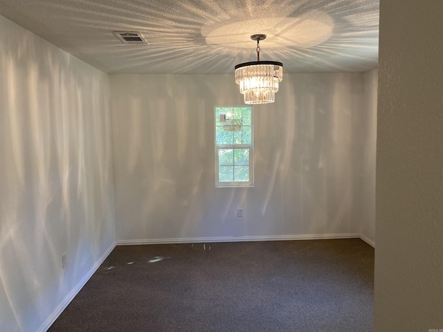 unfurnished room with dark colored carpet and an inviting chandelier