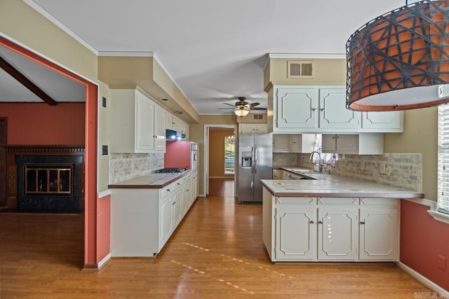 kitchen with white cabinets, appliances with stainless steel finishes, kitchen peninsula, and decorative backsplash