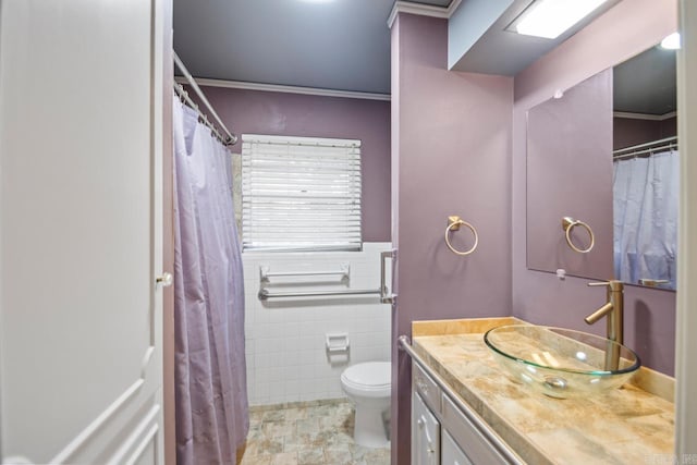 bathroom featuring vanity, toilet, crown molding, and tile walls