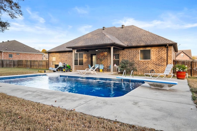 view of swimming pool with a diving board, a patio area, and a lawn