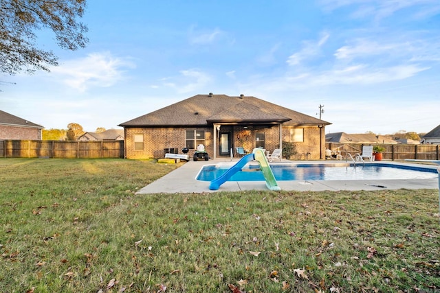 view of pool with a yard, a water slide, and a patio