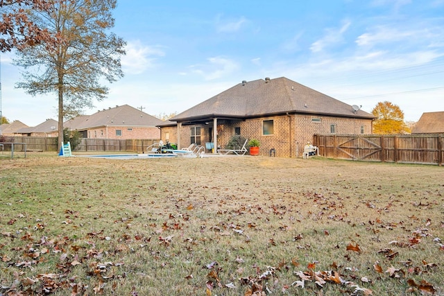 rear view of property with a fenced in pool and a lawn