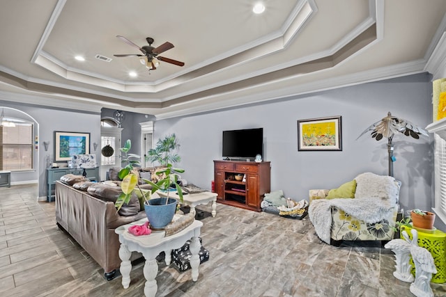 living room with a raised ceiling, crown molding, ceiling fan, and light hardwood / wood-style floors