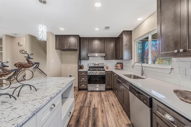 kitchen featuring white cabinetry, sink, light stone countertops, dark hardwood / wood-style floors, and appliances with stainless steel finishes