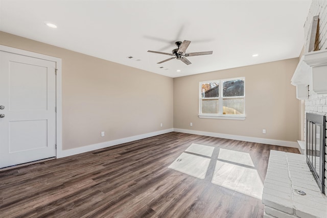 unfurnished living room featuring dark hardwood / wood-style flooring, ceiling fan, and a fireplace