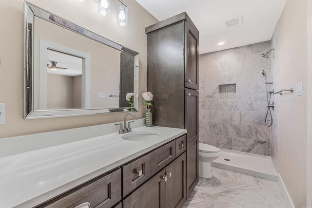 bathroom featuring tiled shower, vanity, toilet, and ceiling fan