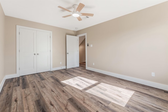 unfurnished bedroom featuring wood-type flooring, a closet, and ceiling fan