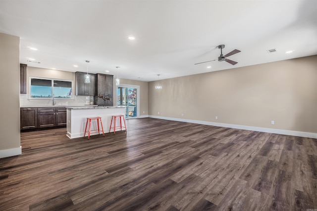 unfurnished living room featuring ceiling fan, sink, and dark wood-type flooring