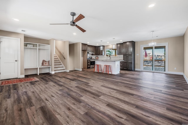 unfurnished living room featuring plenty of natural light, dark wood-type flooring, and ceiling fan with notable chandelier