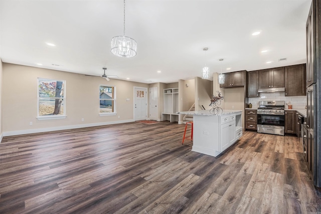 kitchen featuring light stone countertops, stainless steel range oven, pendant lighting, a breakfast bar area, and a kitchen island