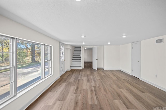 unfurnished living room featuring light hardwood / wood-style flooring and a textured ceiling