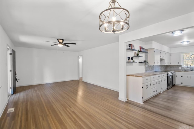 kitchen with white cabinets, light wood-type flooring, hanging light fixtures, and electric stove