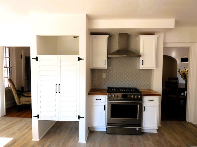 kitchen featuring butcher block counters, wall chimney exhaust hood, dark hardwood / wood-style flooring, high end stainless steel range, and white cabinets