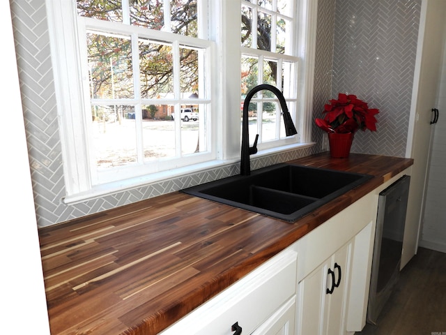 kitchen featuring dark wood-type flooring, sink, dishwasher, white cabinetry, and butcher block counters